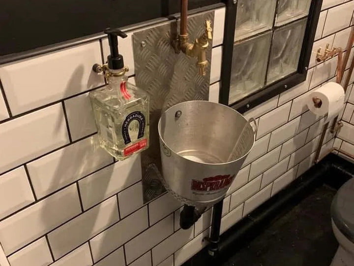 Commercial washroom finished with exposed copper pipework and a trough sink