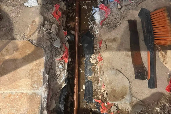 Copper pipework exposed beneath a floor to repair a traced water leak